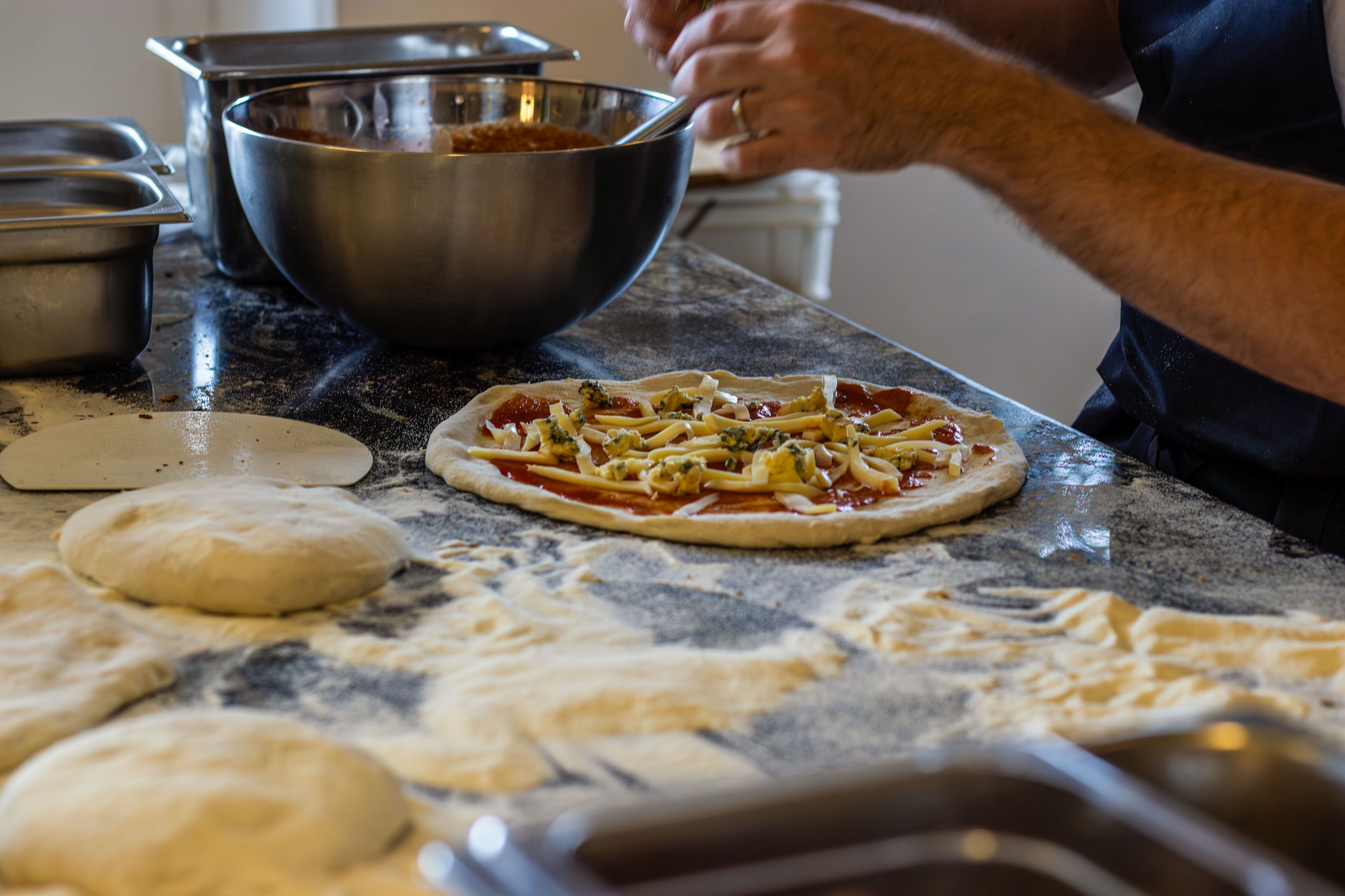 Preparación de pizza con ingredientes sobre la mesada