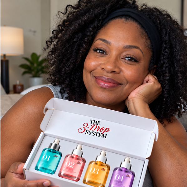 Woman with long curly hair and a black headband holding the open The 3-Drop System box