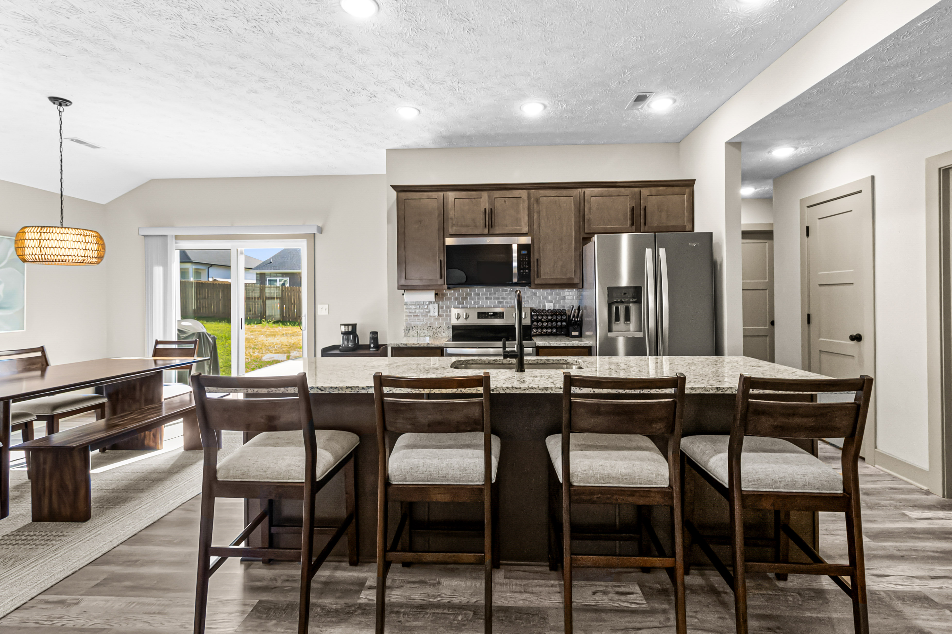 Bright kitchen with granite island, bar stools, and adjoining dining area
