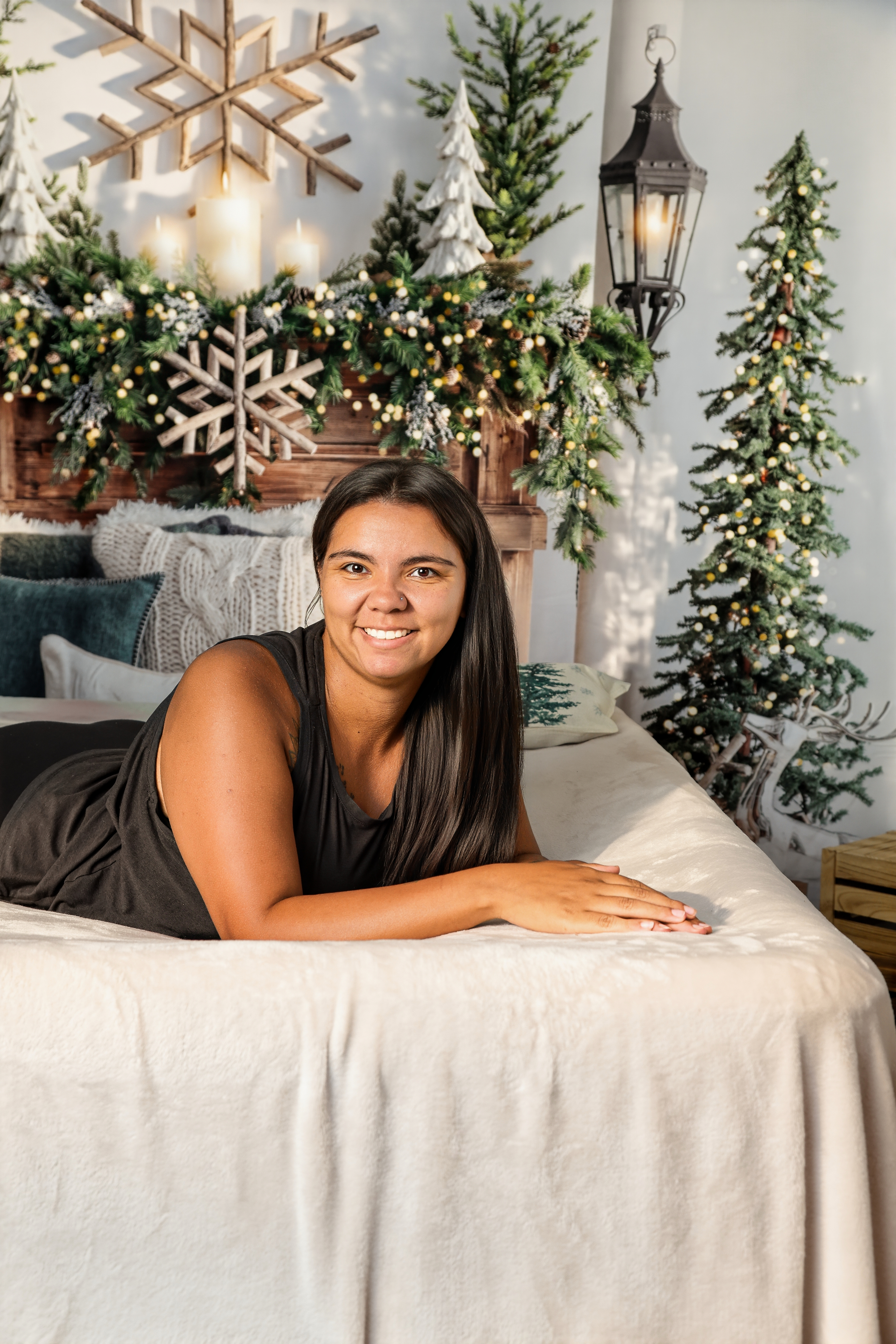 Woman relaxing on a cozy bed beneath a garland-draped headboard on the holiday studio set