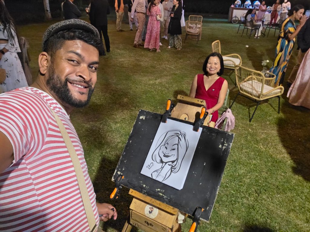 Warren Le Caricaturiste — artiste en bretelles devant son chevalet, caricature live Île Maurice par Inovaci