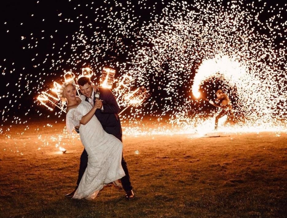 Man of Fire — Cracheur de feu créant une gerbe d'étincelles dorées derrière un couple de mariés, spectacle de feu Île Maurice par Inovaci