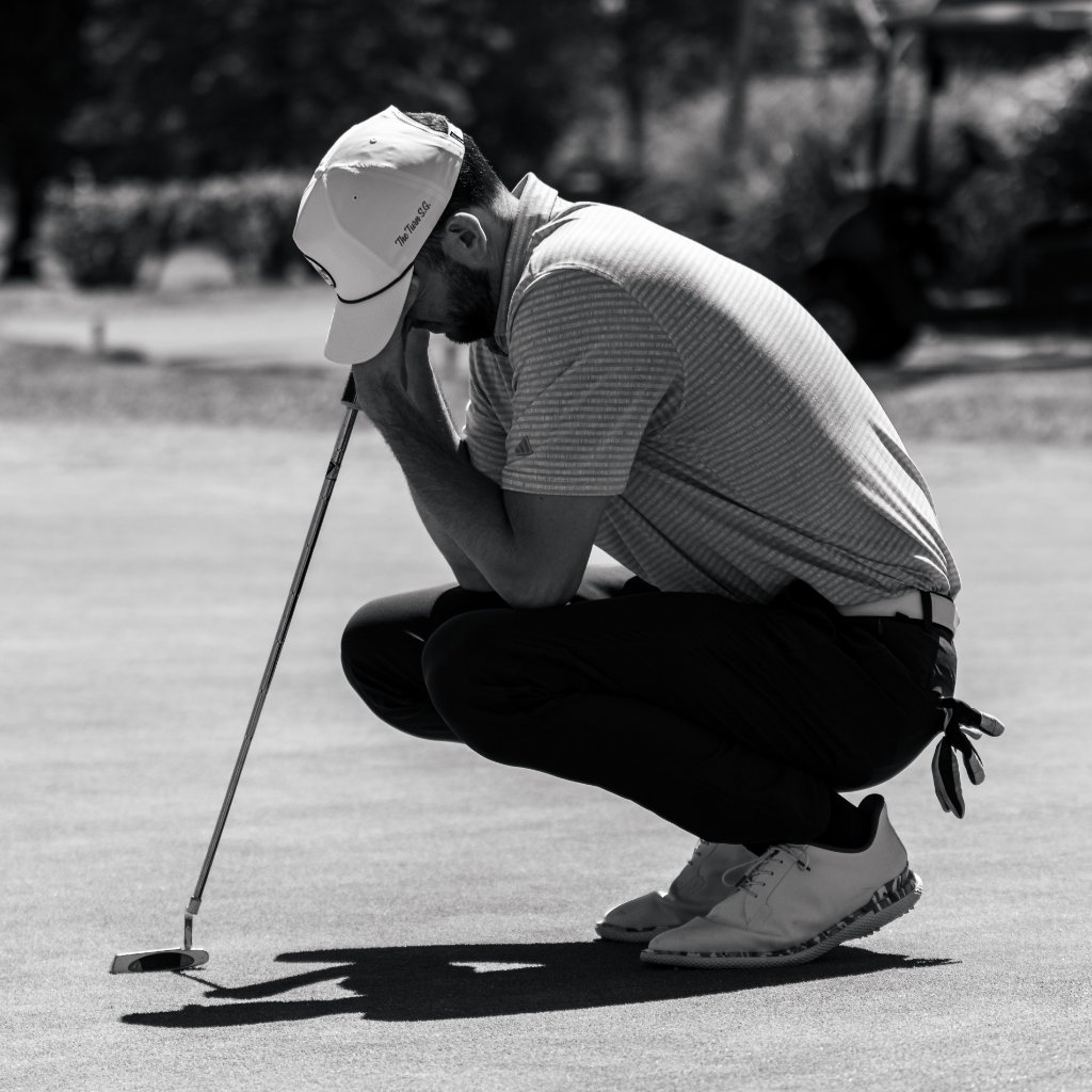 Black and white photo of golfer crouching in concentration