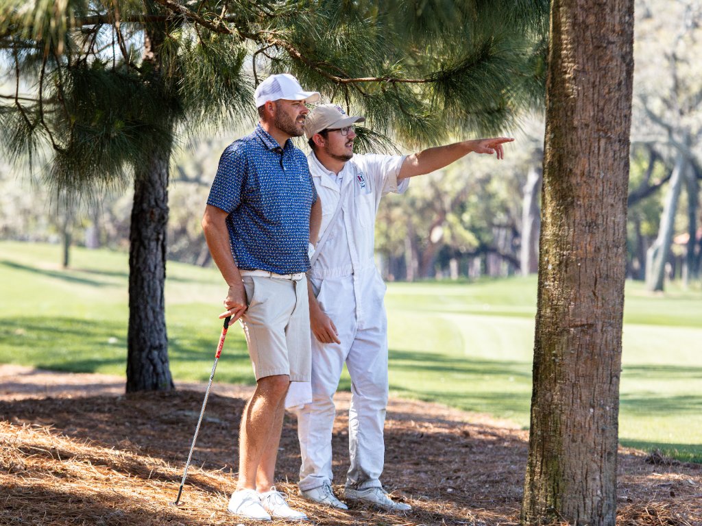Golfer in blue polo shirt framed through a golf cart