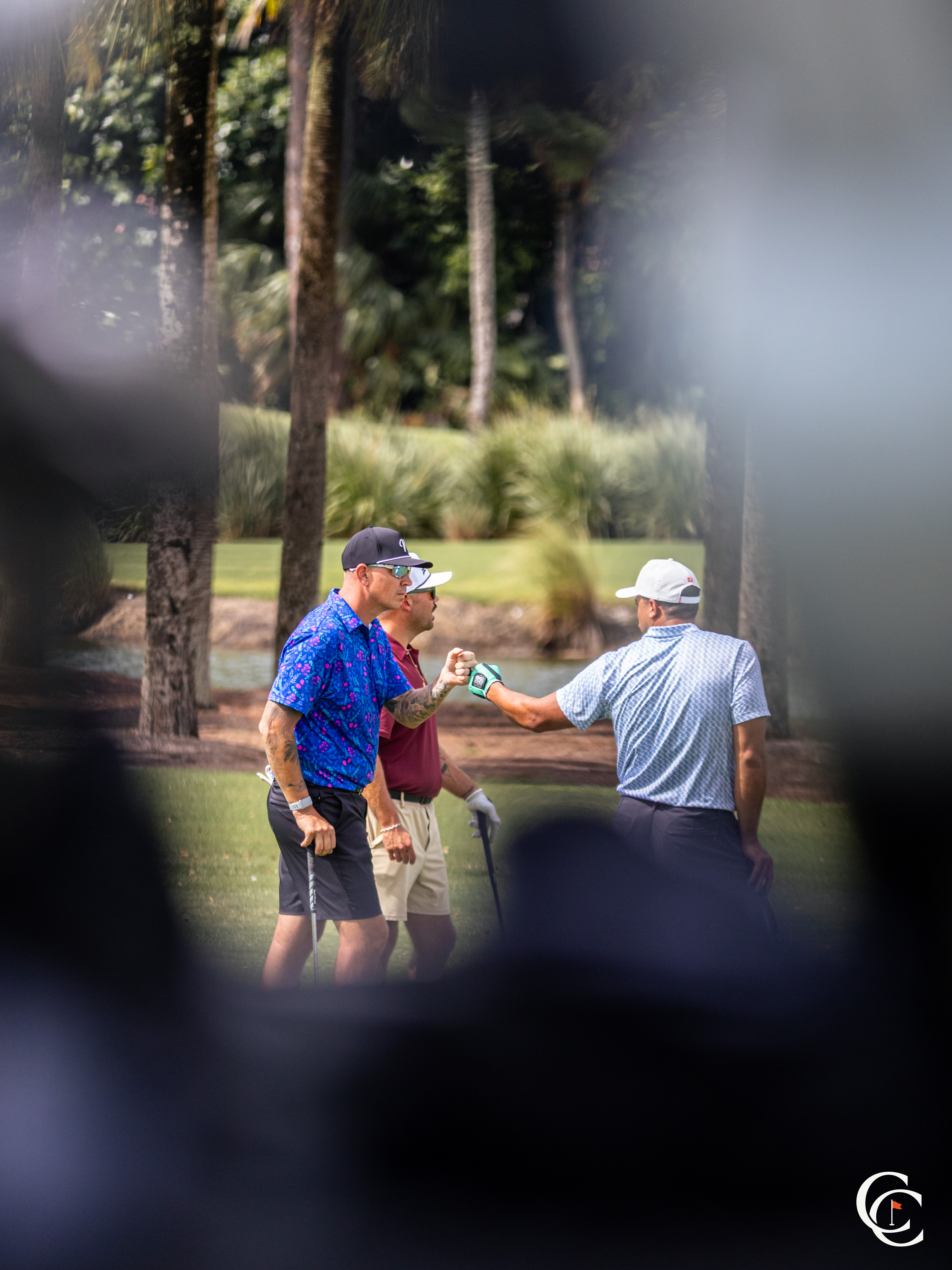 Three golfers sharing a fist bump on the green