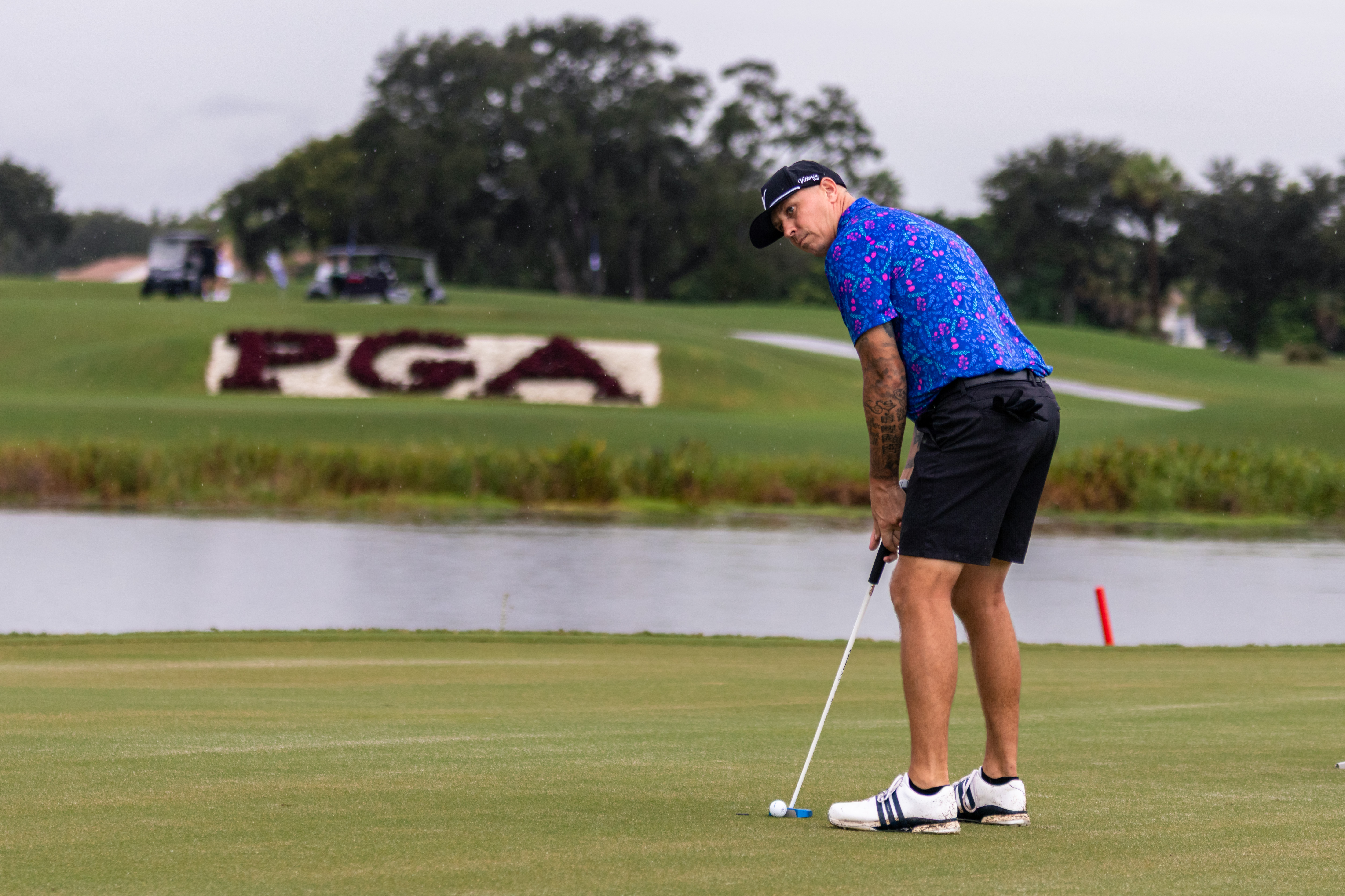 Golfer standing over a putt with the PGA National course in the background