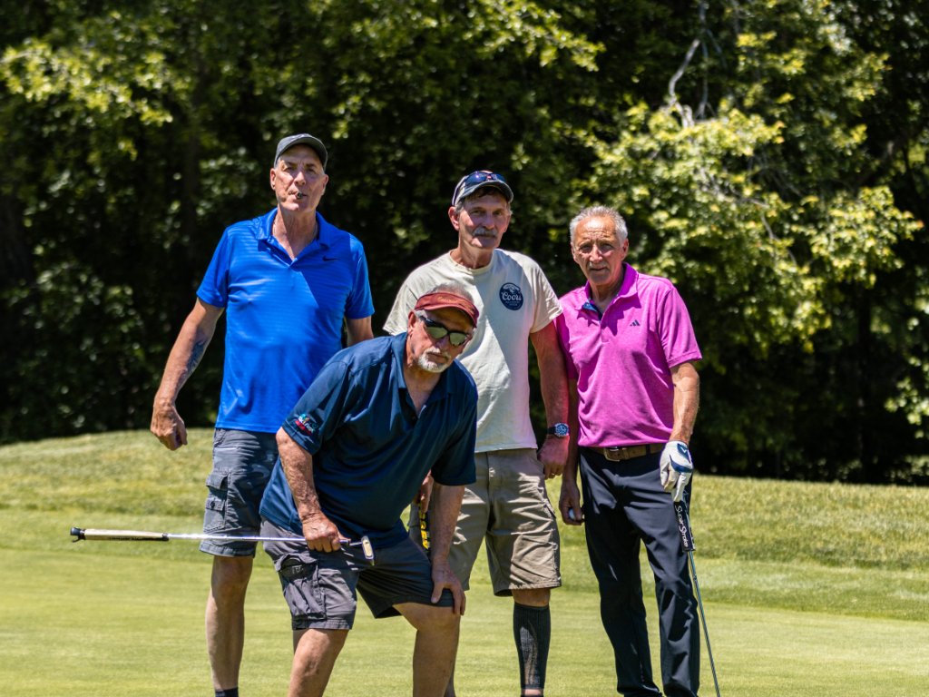 Four men posing on the green with putters