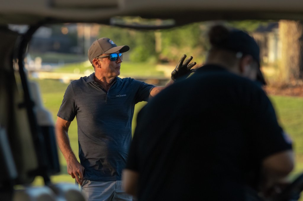 Golfer talking with caddie in the trees pointing to the fairway