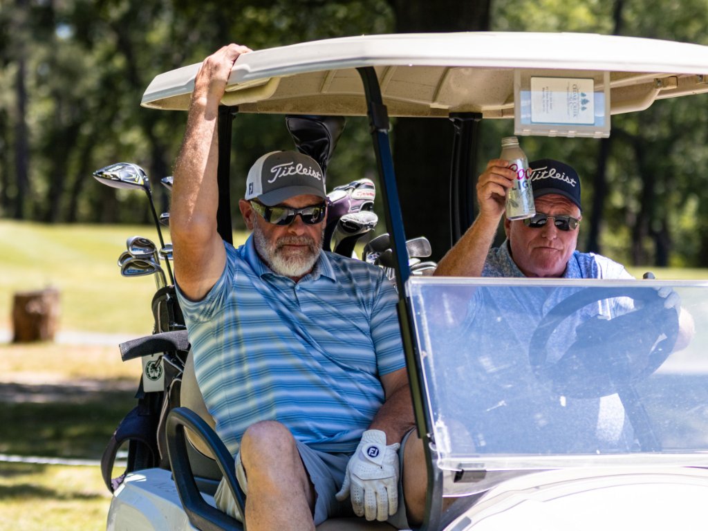 Two men in a white golf cart with Coors Light at Cedar Creek