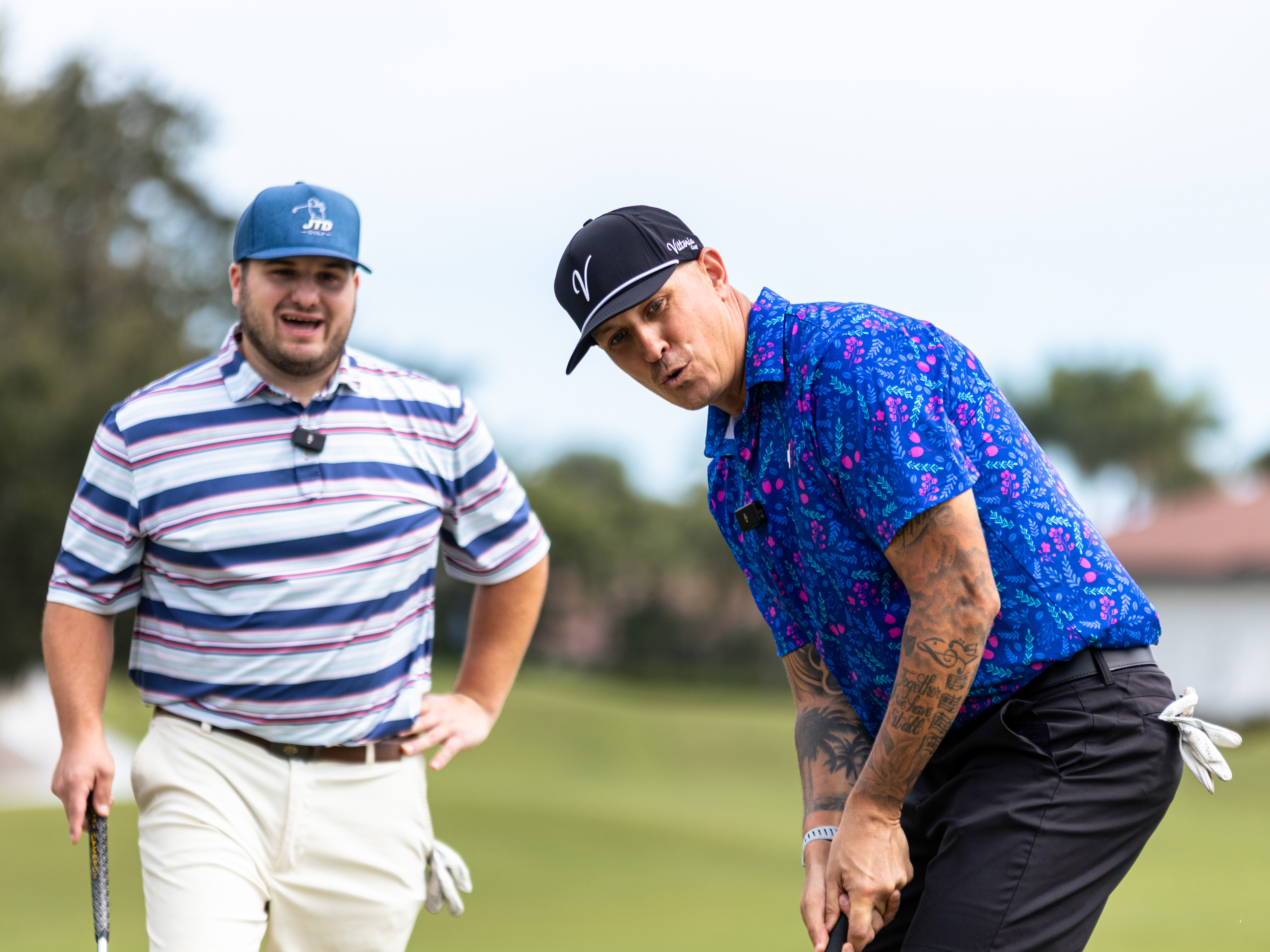 Two golfers on the green, one reading a putt while the other watches