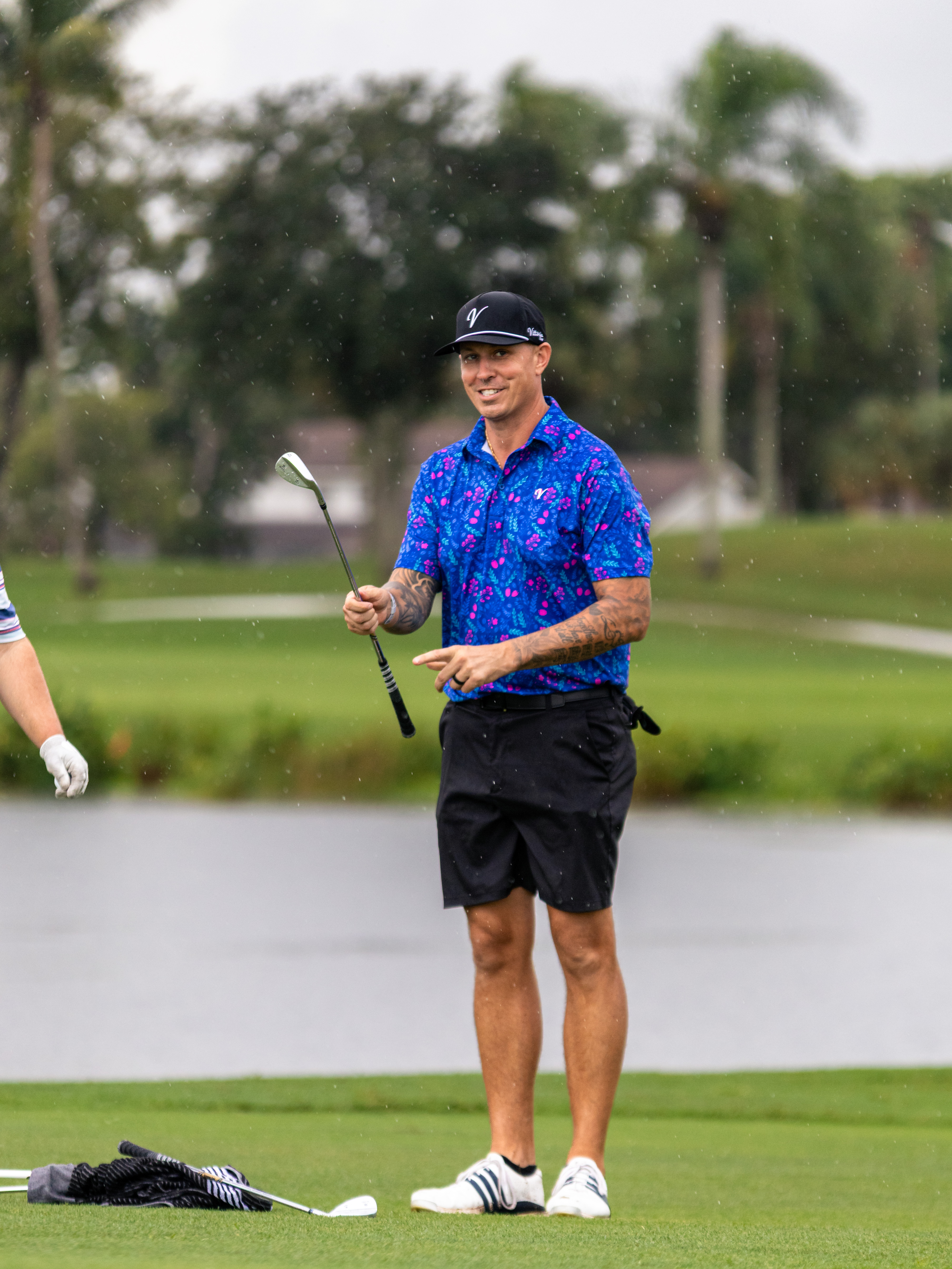 Golfer in blue floral polo smiling and pointing on the putting green