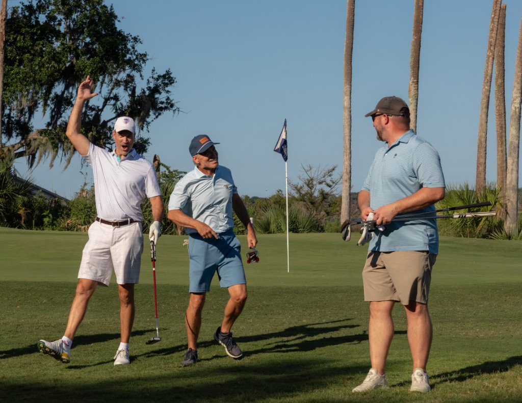 Three golfers celebrating on the green at golden hour