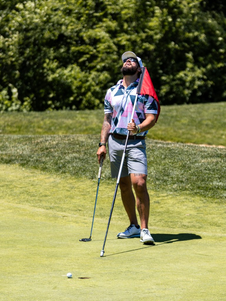 Golfer reacting dramatically after a missed putt with the flag