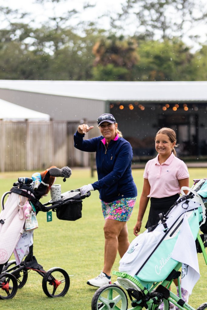 Mother and daughter smiling with their golf push carts on the fairway
