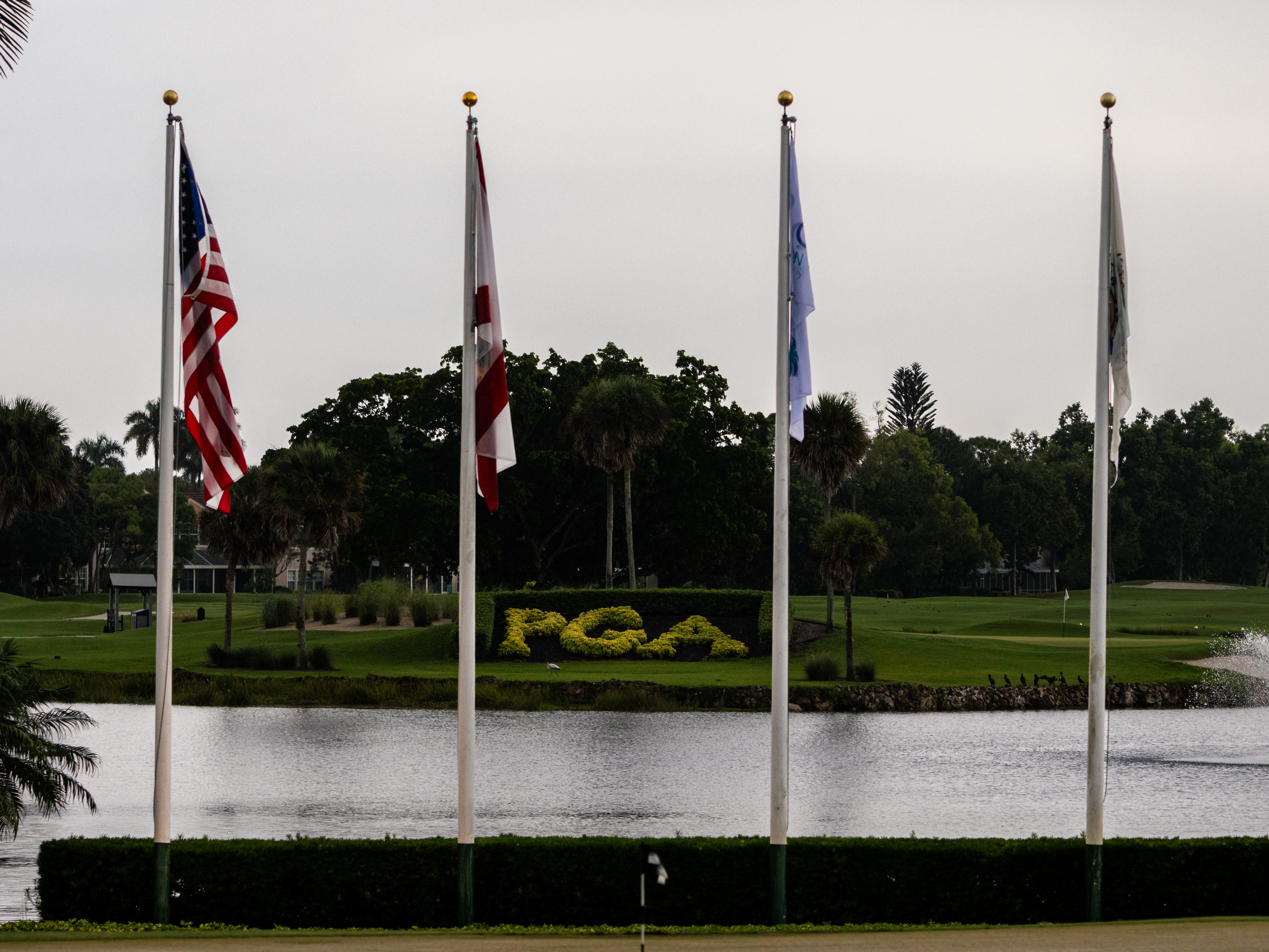 Four flagpoles overlooking a pond and the PGA course