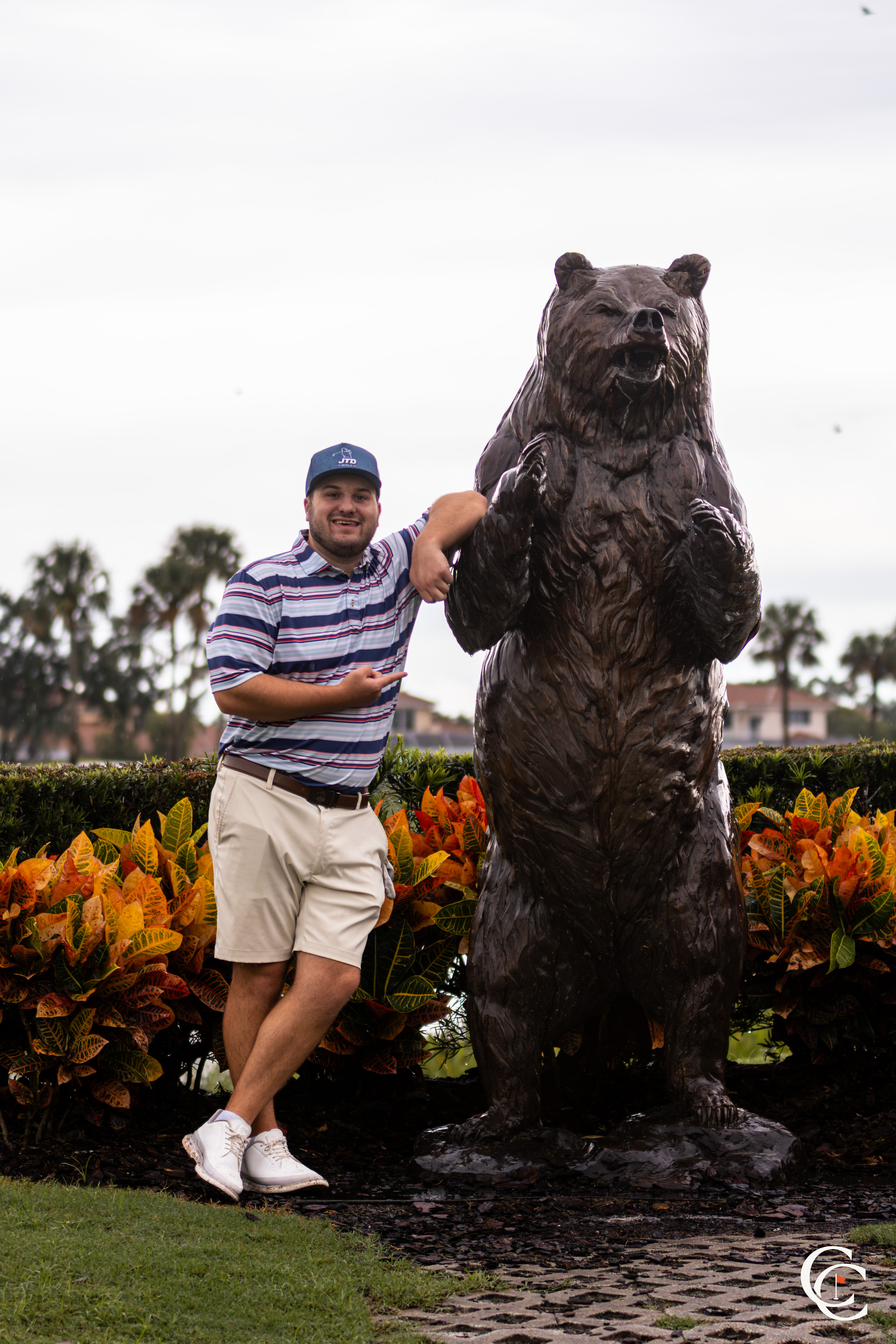 Golfer posing next to a bronze bear sculpture on the course