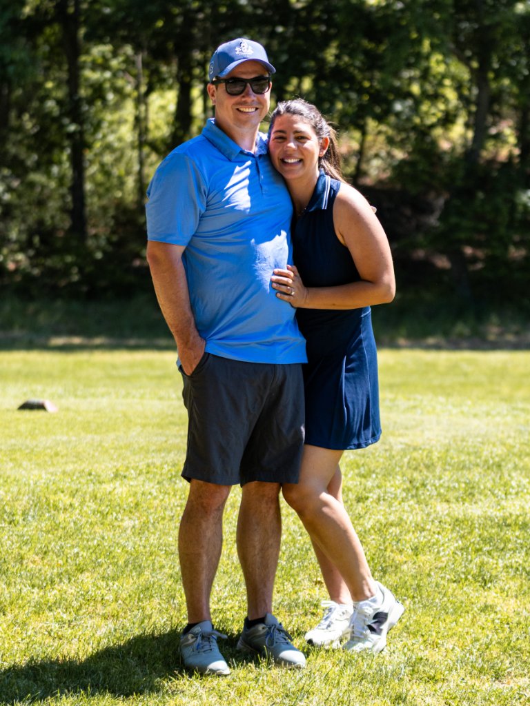 Man and woman smiling with arms around each other on the course
