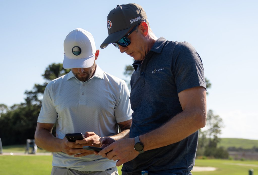 Two golfers reviewing photos on a phone on the course