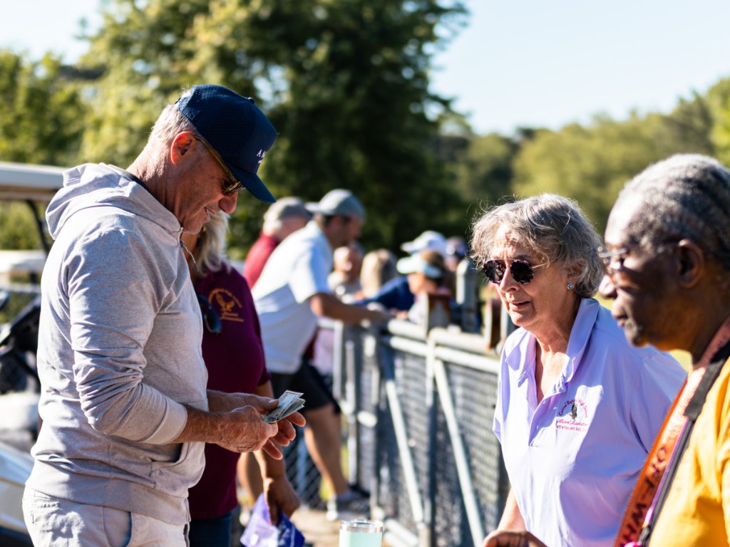 Man counting cash while woman in lavender polo looks on