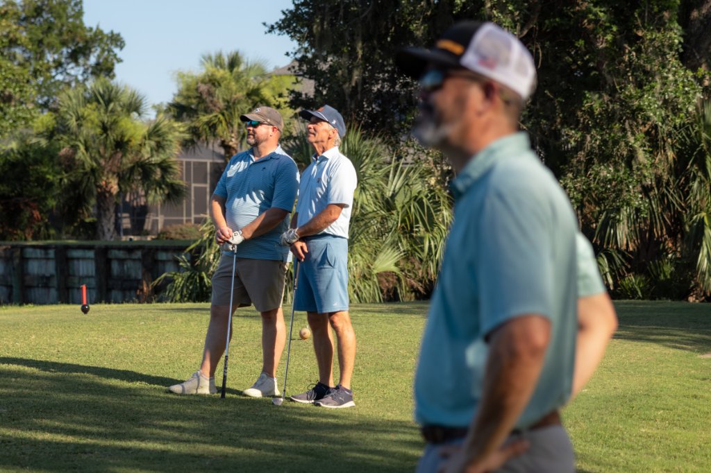 Group watching a shot from the fairway at sunset