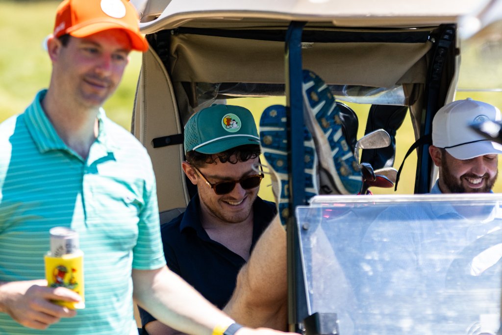 Friends laughing around a golf cart