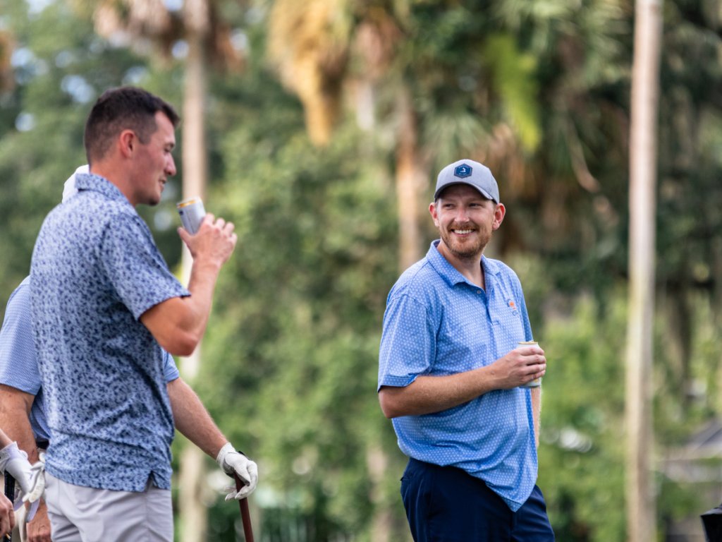 Two golfers laughing and sharing a drink between holes