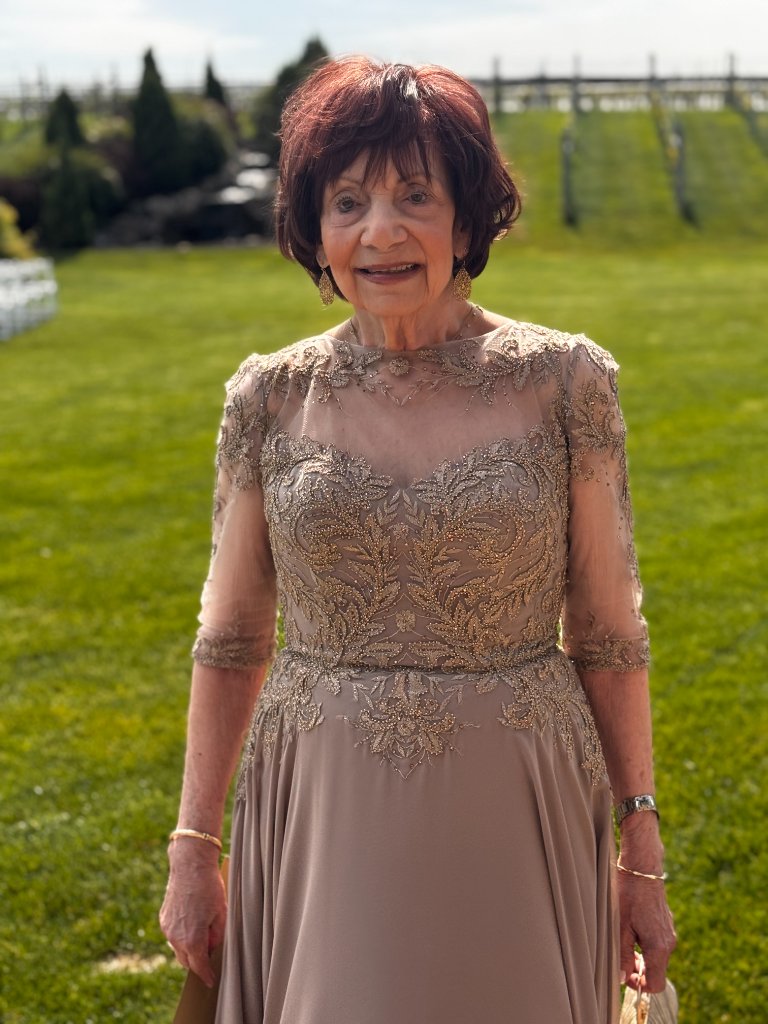 Client Arlene smiling in an elegant gown, showcasing her hair topper styled by Shaina