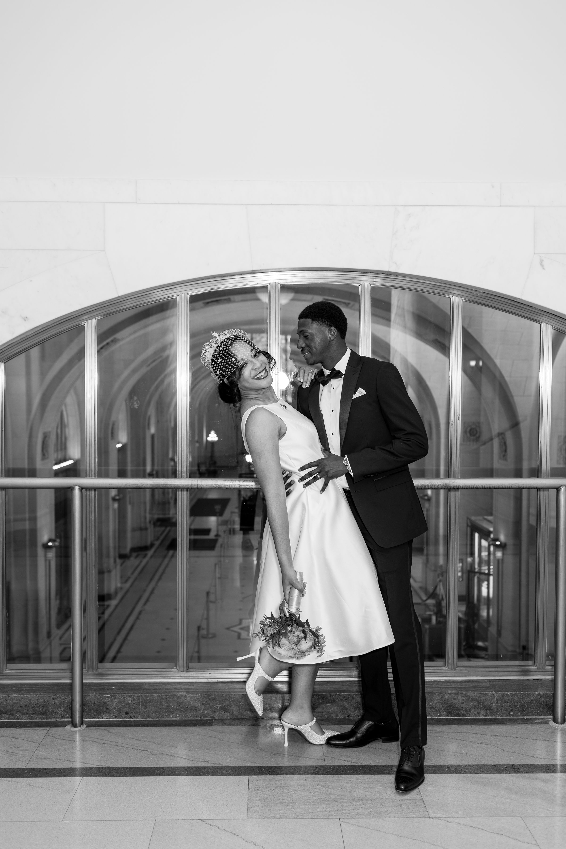 Couple in a joyful pose behind an arched window
