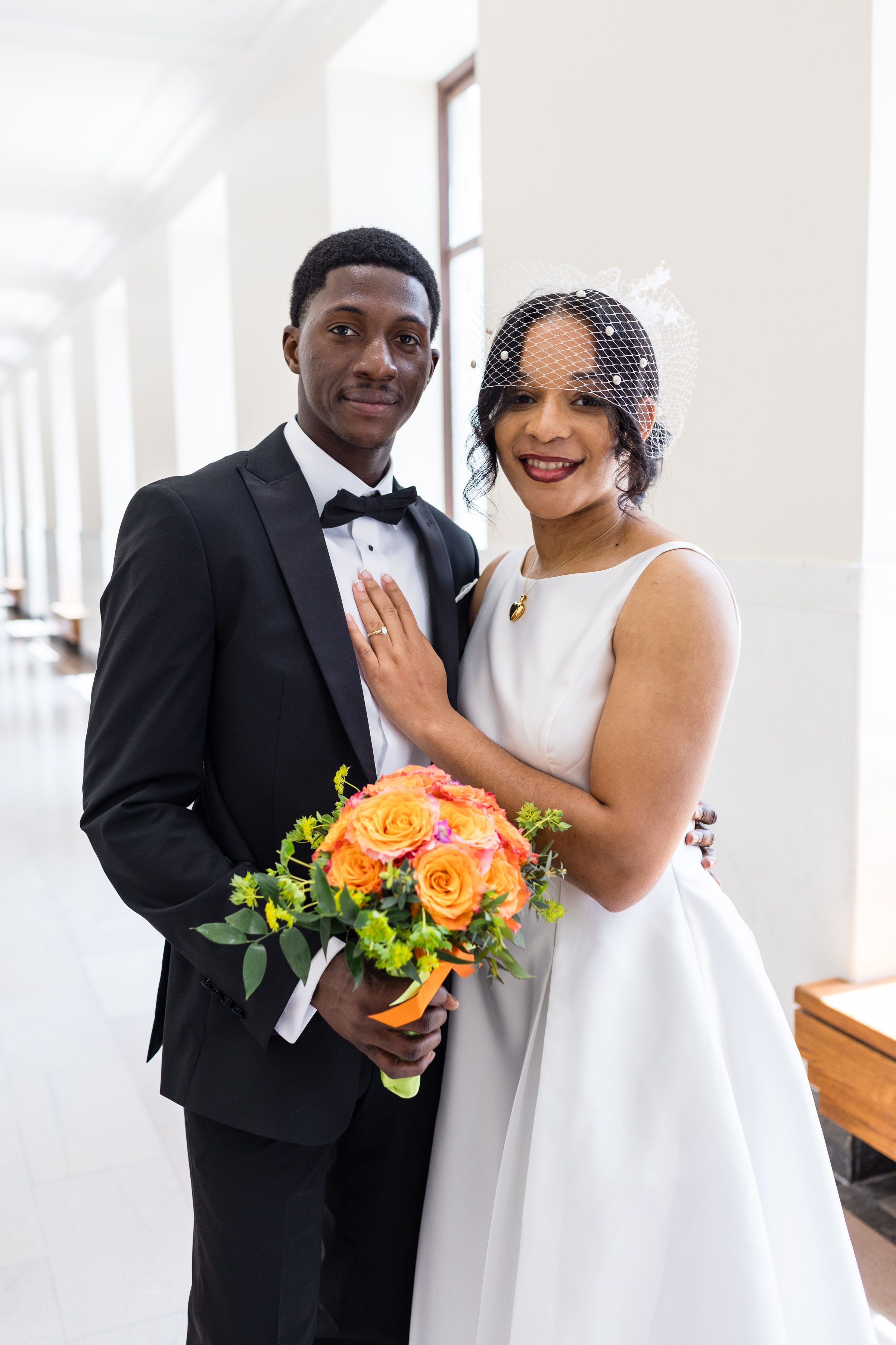 Couple in wedding attire by a tall window