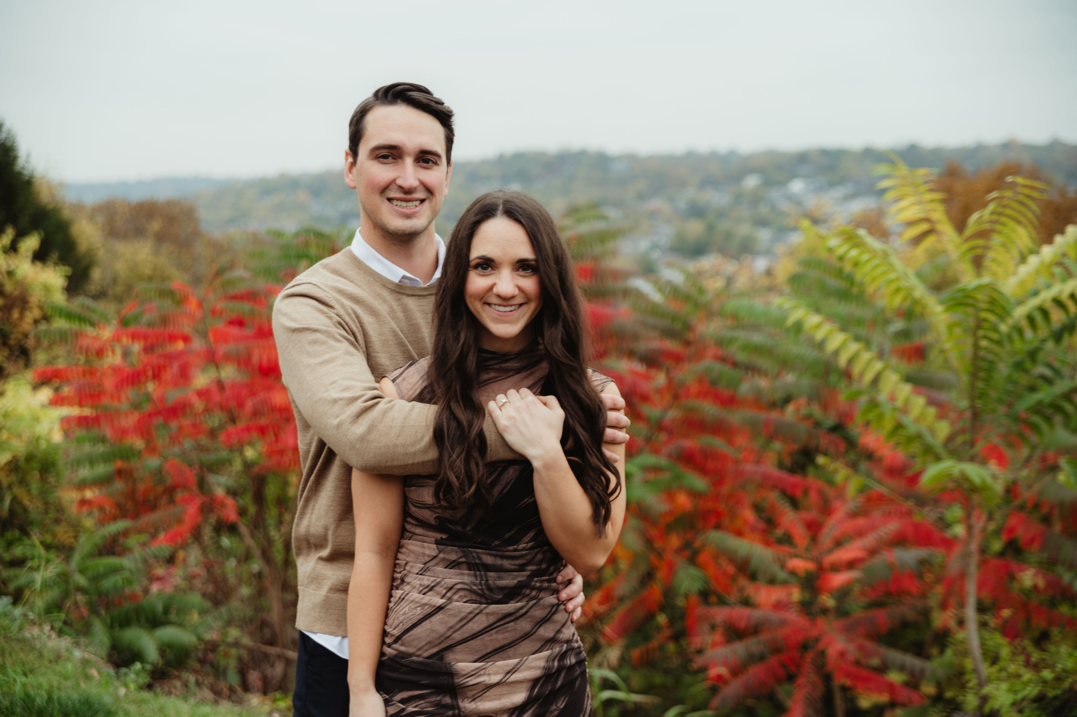 Couple in front of vibrant autumn foliage
