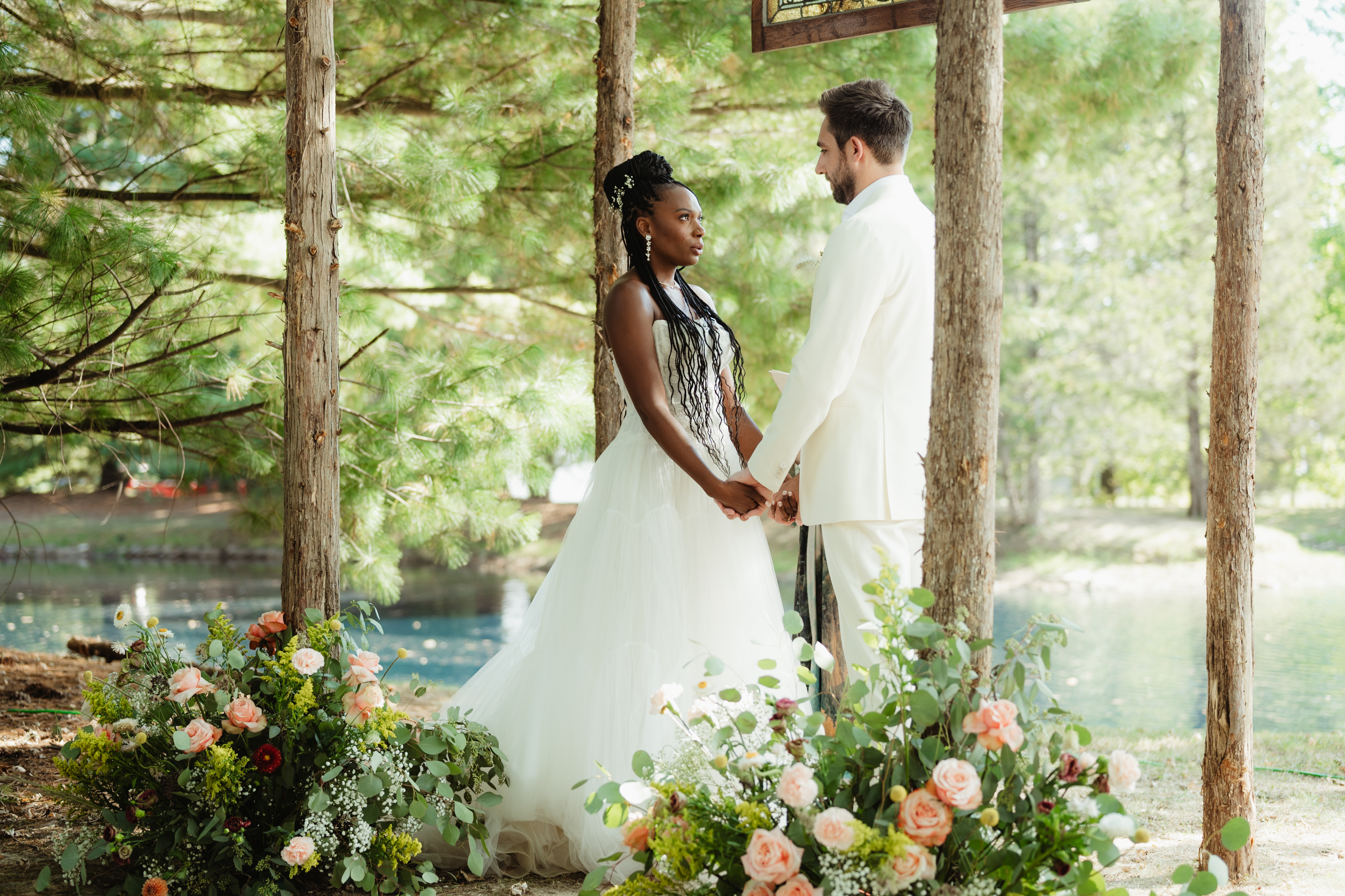 Couple holding hands between trees by the water