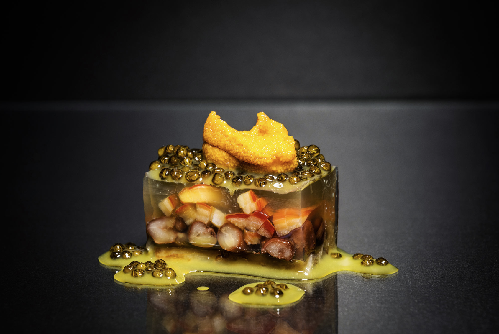 Terrine aus Seeigel und Kaviar auf dunkler, reflektierender Oberfläche