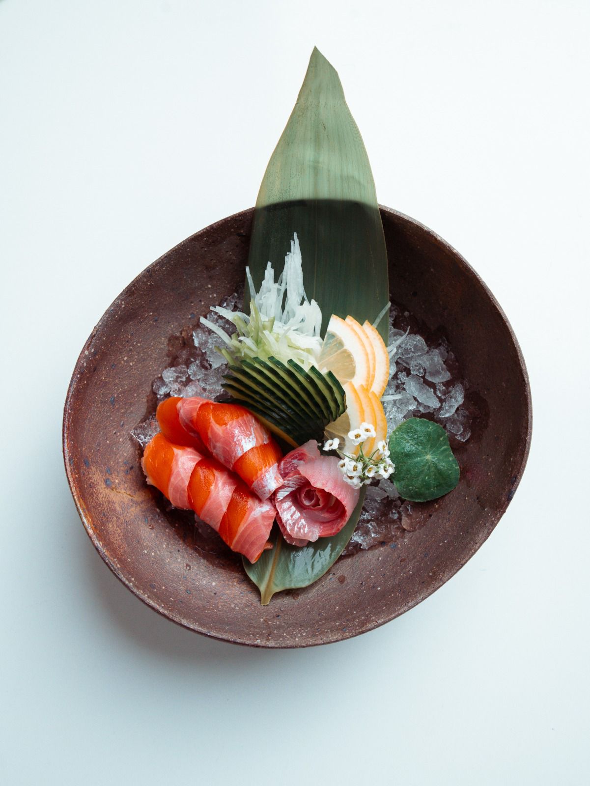 Sashimi mit Lachs und weissem Fisch auf Eis in einer Keramikschale