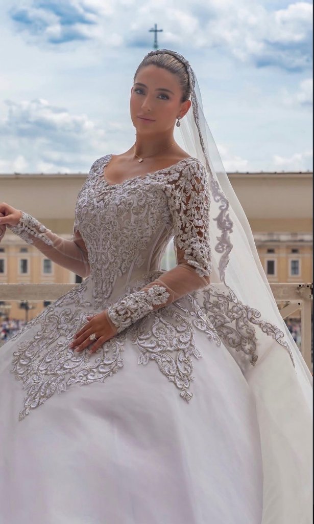 Bride praying in ornate lace wedding gown with tiara and cathedral veil, bridal gown alterations Boynton Beach