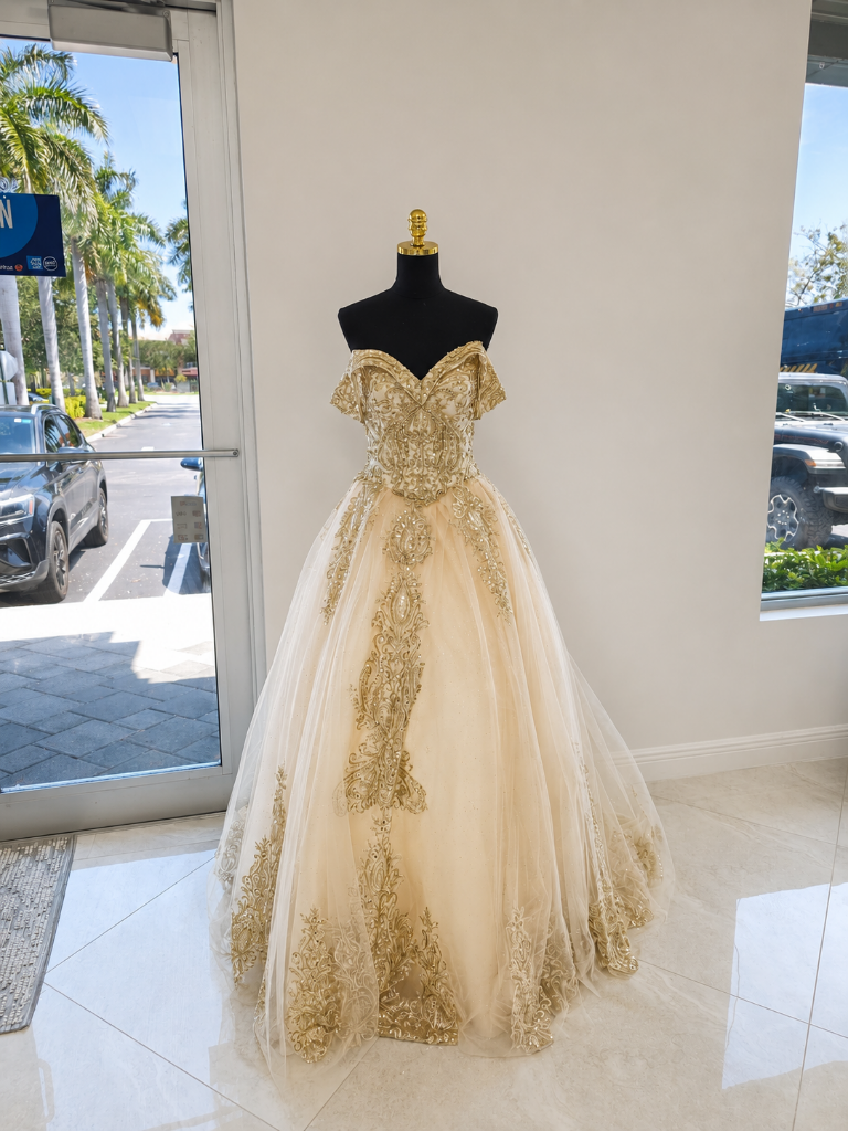 Gold champagne quinceañera ball gown with intricate gold lace applique on dress form in Boynton Beach boutique showroom at Bridal and Couture Alterations