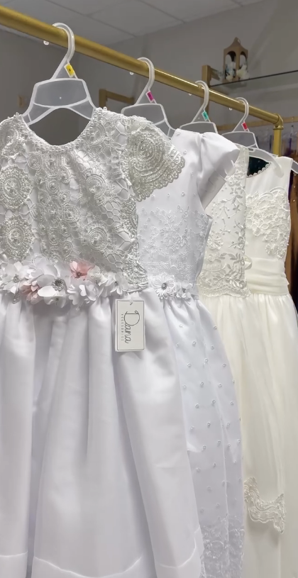 Flower girl and baptism dresses with lace detail hanging on boutique rack