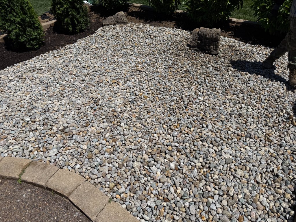Decorative river rock landscaping bed with concrete edging