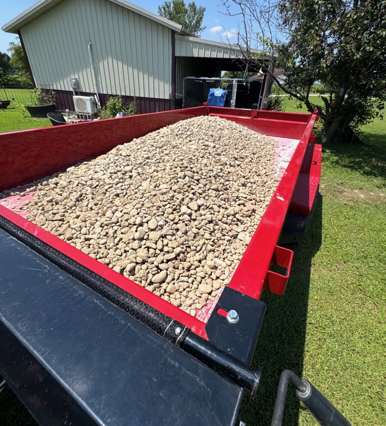 Red dump trailer loaded with river stone for delivery