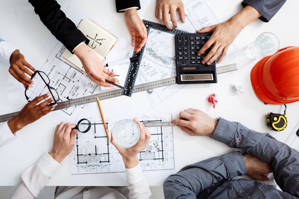 QS consultants reviewing blueprints, BOQs and a technical estimate on a white table