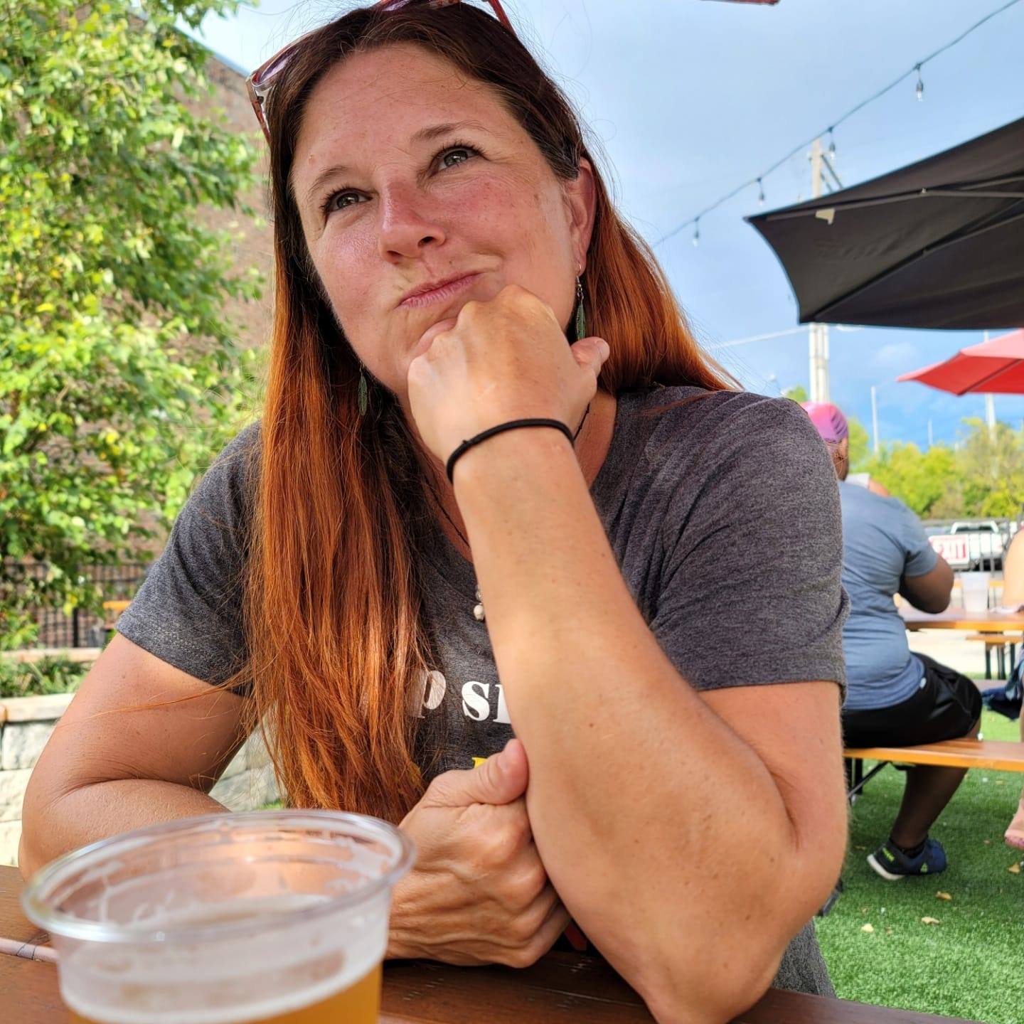 Debbie thinking — chin resting on hand, outdoors at golden hour