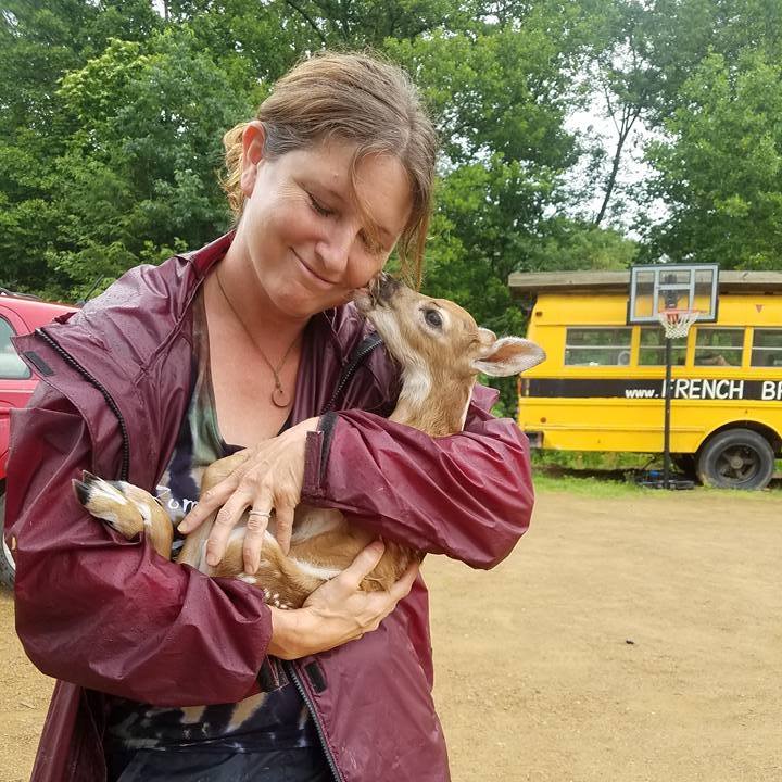 A real moment in the field — holding a fawn beside a school bus