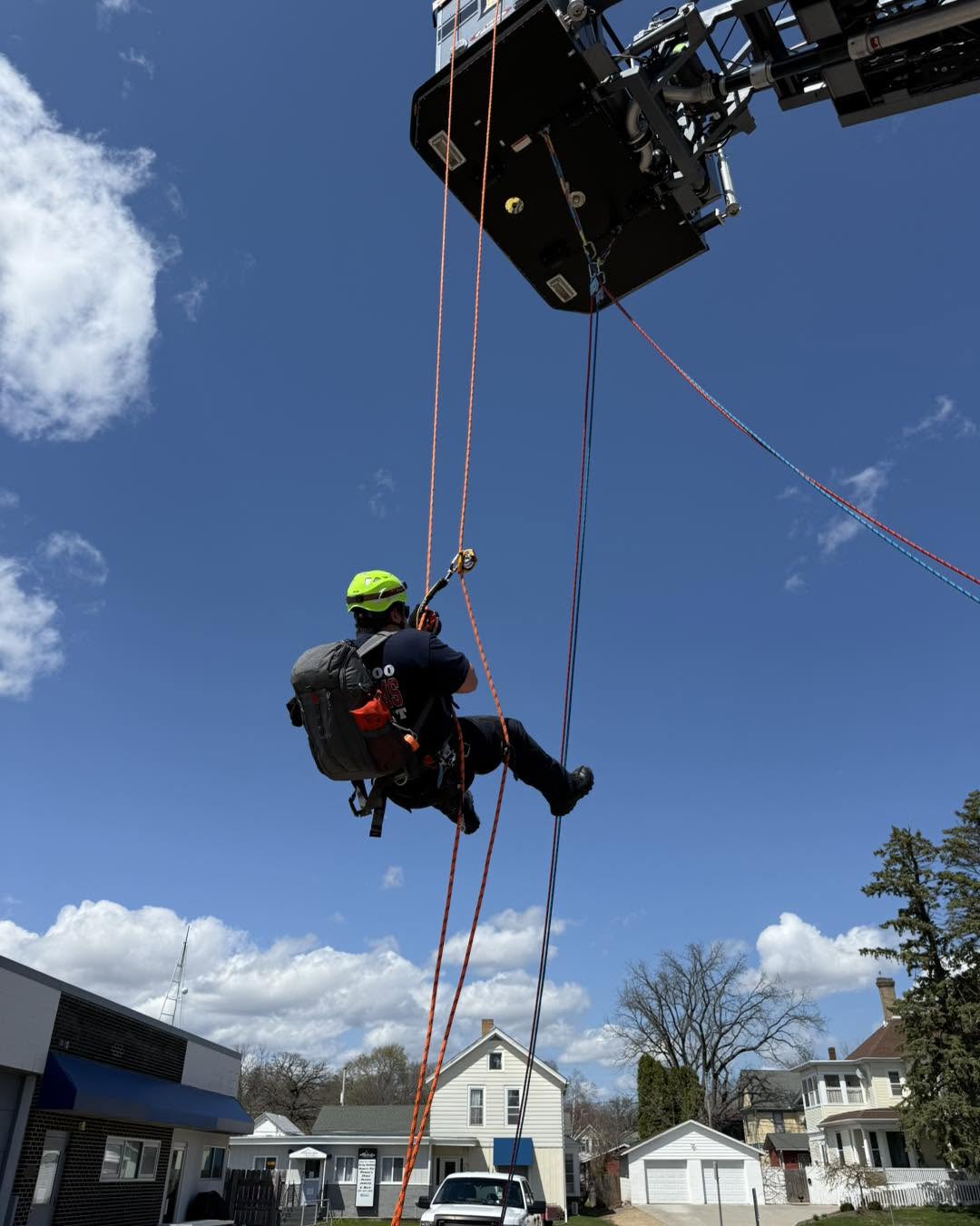 Firefighter suspended on rope during a high-angle rescue drill.