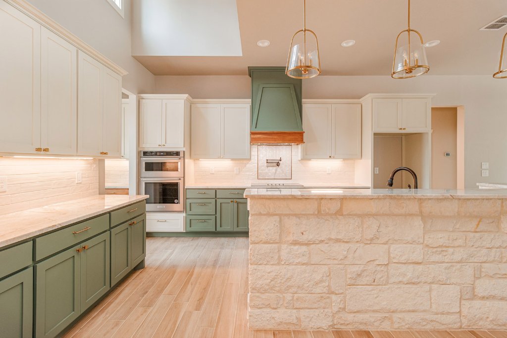 Sage green and cream custom kitchen cabinets with stone island by CJ Cabinets in San Antonio
