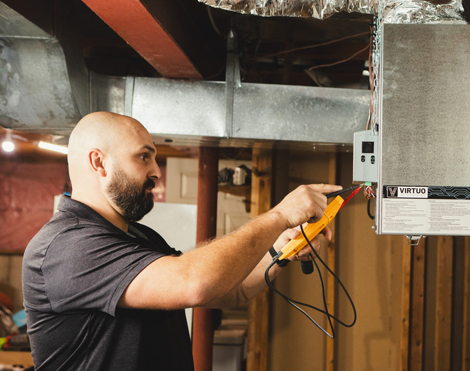 RBM technician testing an ERV system unit in a basement