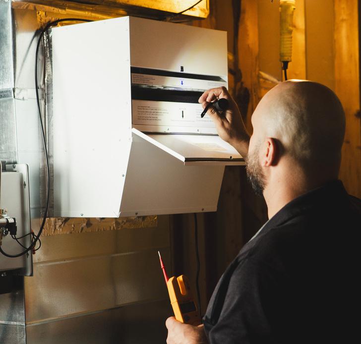 RBM technician inspecting a whole-home HEPA filtration unit