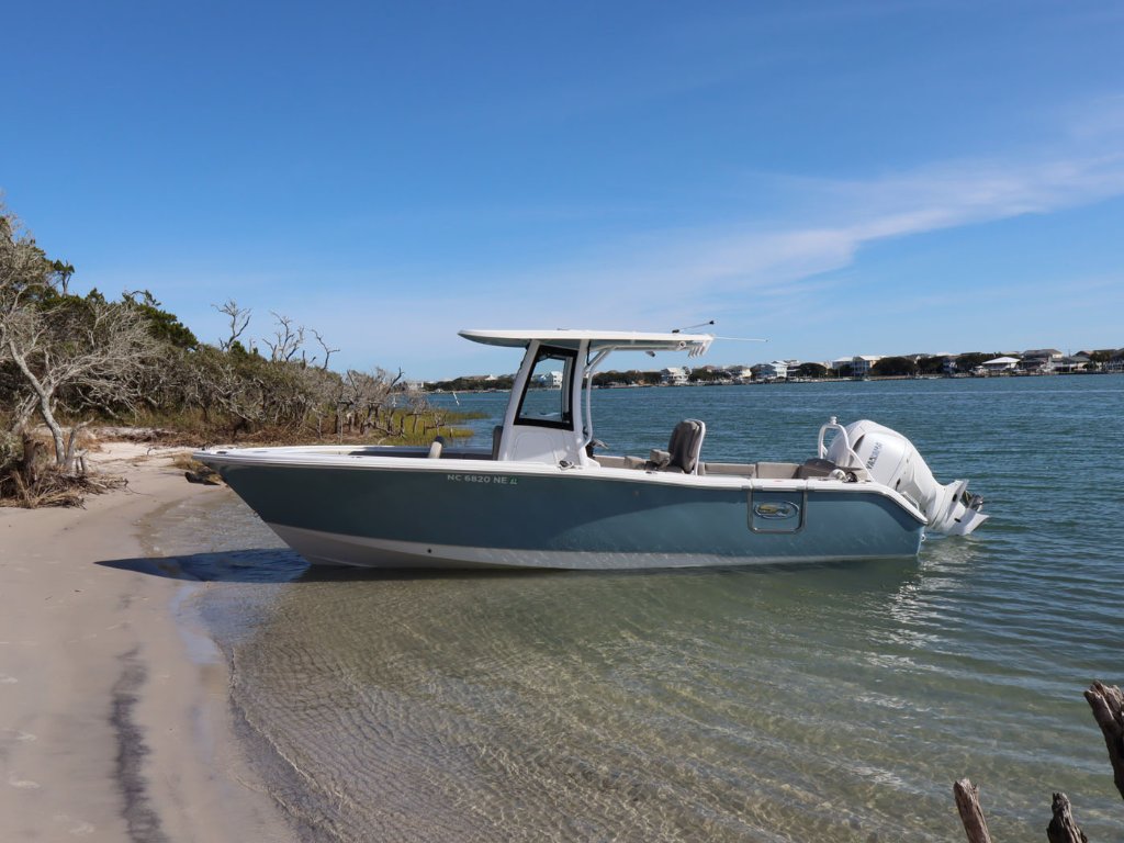 Center-console boat beached on a sandy shore in shallow clear water