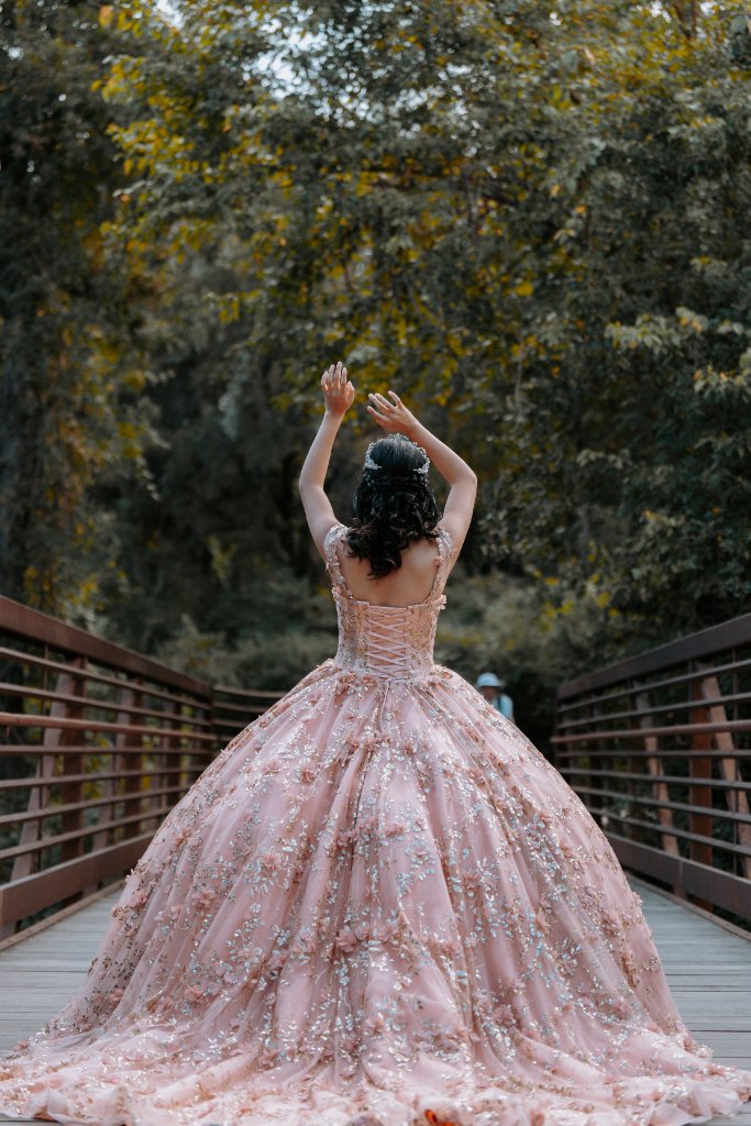 Quinceañera in blush pink gown on a wooden bridge