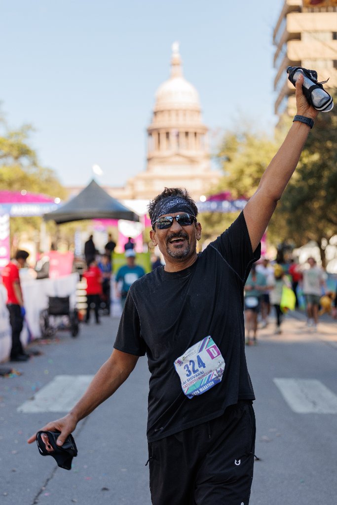 Runner celebrating with Texas Capitol dome behind