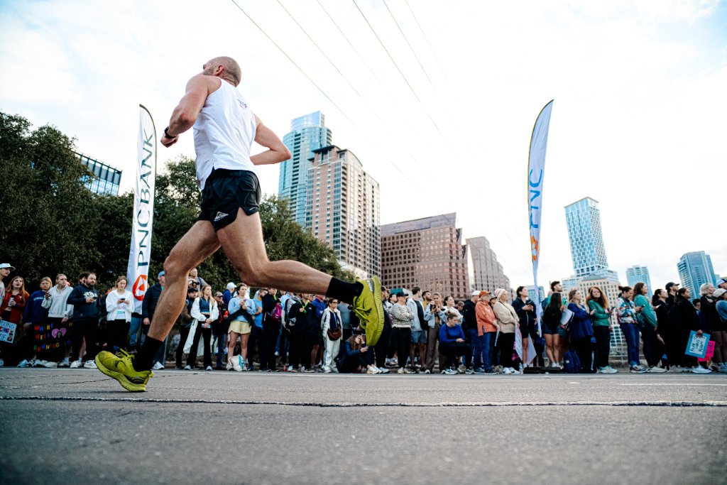 Runner passing cheering crowd with Austin skyline
