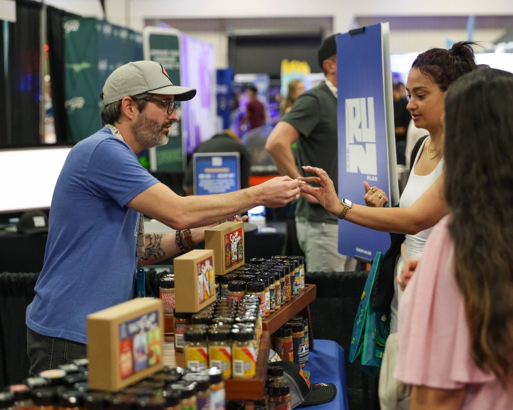 Exhibitor handing sample to attendee at Austin Marathon Expo